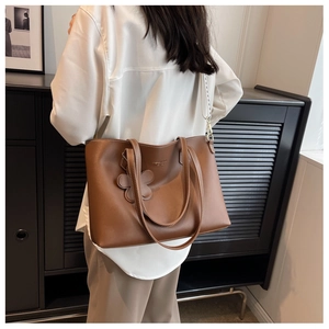 Detail of caramel tote bag with contrast stitching and floral charm accessory