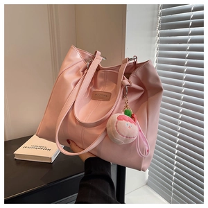 Dettaglio della borsa tote rosa in ecopelle con trama litchi e ciondolo a forma di pesca