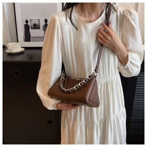 Detail of a dark brown pebble leather shoulder bag with a chunky silver chain strap