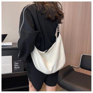 Detail of white moon-shaped canvas bag featuring black chunky chain and fashion label