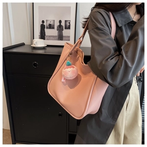 Pink PU leather tote bag close-up with a cute donut plush charm on the shoulder strap