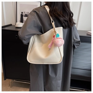 Creamy white tote bag detail featuring a soft leather texture and pink plush charm