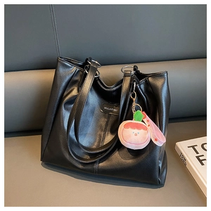 Dettaglio della borsa tote in pelle martellata nera con ciondolo a pesca in peluche
