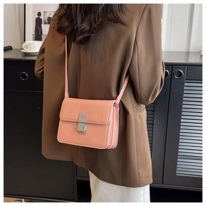 Pink PU leather crossbody bag with silver metal lock shown on person in a trendy setting