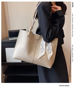Close-up of beige litchi grain tote bag with bear print scarf on a professional model