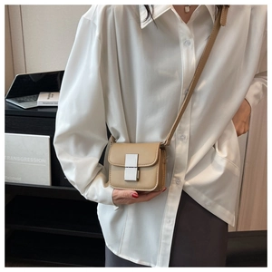 Detail of khaki leather crossbody bag with silver metallic buckle on a white shirt