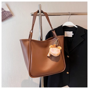 Deep brown tote bag detail with matte texture and cute pink plush bear pendant charm