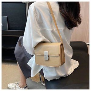 Detail of light beige square crossbody bag featuring a vertical silver metal clasp
