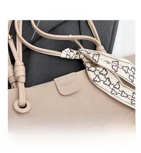 Close-up of beige lychee leather tote bag with silk scarf detail and fine stitching