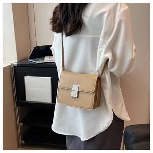 Side view of a khaki leather flap crossbody bag with silver buckle worn by a model