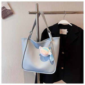 Detail of light blue faux leather tote bag with a cute plush bear charm for daily commute