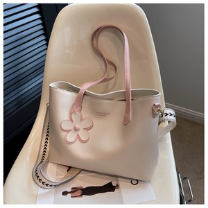 Close-up of white leather tote bag with pink handles and patterned wide crossbody strap