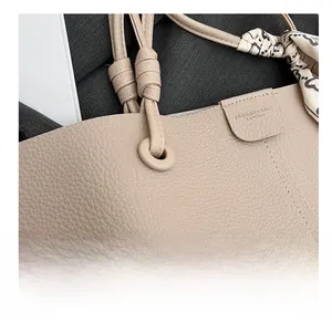 Detail of beige lychee grain leather tote bag featuring a floral scarf wrapped on a knotted strap