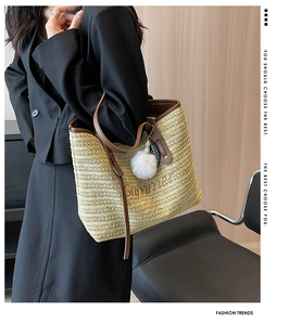 Detail of straw tote bag with Summer embroidery, brown leather handles and pompom charm