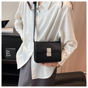 Detail of a black leather crossbody square bag with a silver rectangular metal clasp closure