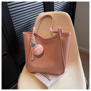 Pink leather tote bag detail with long shoulder straps and peach plush charm