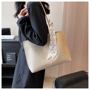 Detailed macro view of litchi texture leather tote bag with decorative bear silk scarf