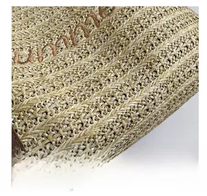 Detailed close-up of natural straw weave texture and brown leather trim on tote bag