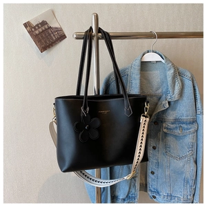 Detail of black tote bag with white stitching, gold hardware and wide canvas strap