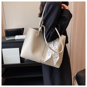 Detailed view of beige tote bag with litchi texture and elegant ribbon decoration