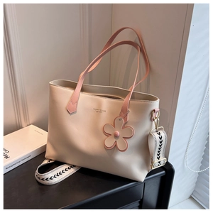 Detail of beige leather tote bag with pink handles and geometric wide shoulder strap