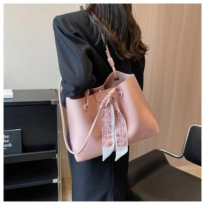 Detail of pink lychee leather tote bag featuring a decorative silk scarf and metal logo