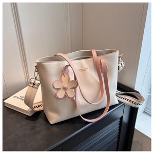 Detail of cream tote bag with pink handles, floral charm and geometric wide strap