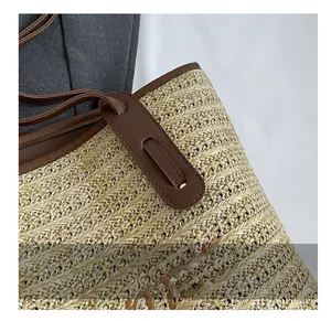 Detailed close-up of woven straw tote bag featuring brown leather strap and fine stitching