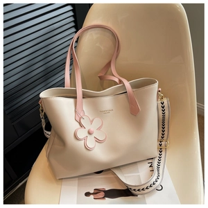 Detail of cream tote bag with contrast pink handles and geometric wide shoulder strap