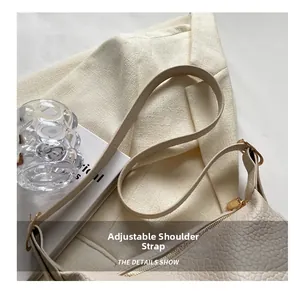 Detail of adjustable shoulder strap and gold hardware on large off-white leather bag