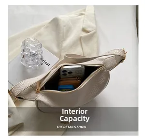 Detail view of large cream crescent bag with croc-embossed texture and spacious interior