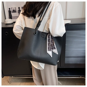 Detail of large black tote bag featuring a decorative bear print scarf on the handle