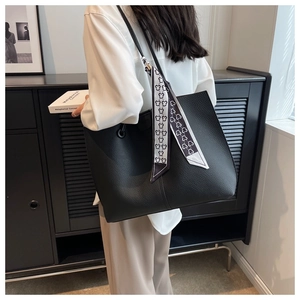 Detailed shot of a black litchi pattern leather tote bag featuring a decorative silk scarf