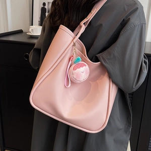 Pink large capacity faux leather tote bag with plush charm shown in a minimalist room