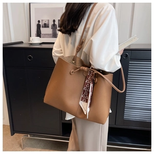 Close-up of brown litchi pattern tote bag featuring decorative heart print silk scarf