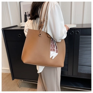 Close-up of brown pebbled leather tote bag with stylish printed silk scarf detail