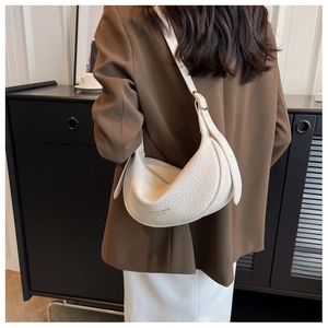 Detail view of white lychee leather texture on a minimalist crescent-shaped shoulder bag