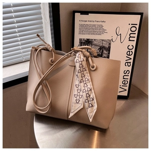 Detail of minimalist cream tote bag with pebble leather texture and decorative scarf