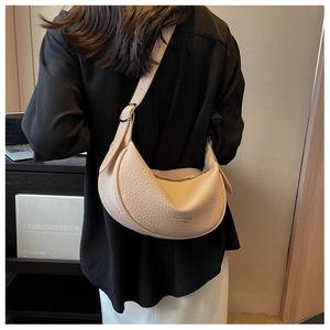 Detail of beige lychee leather half-moon bag featuring gold lettering and adjustable strap