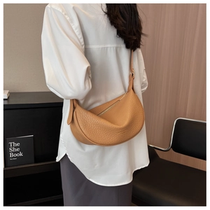 Close-up of a brown saddle bag with litchi texture leather and adjustable shoulder strap
