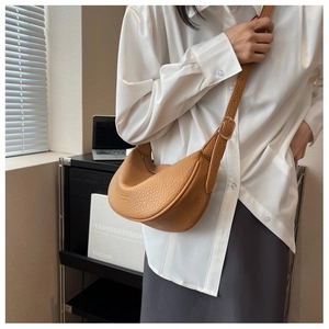 Detail of tan leather crescent bag with gold logo lettering and adjustable strap