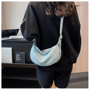 Detail of light blue crescent bag with litchi leather texture and gold metal buckle