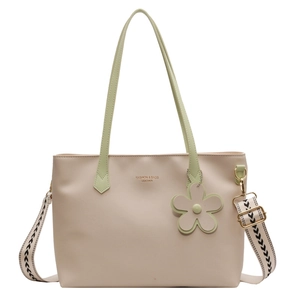 Minimalist beige tote bag with green handles and wide patterned strap shown in full view