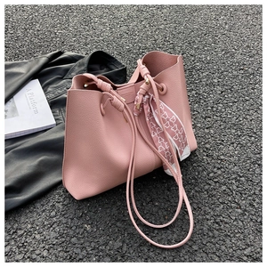 Pink lychee leather tote bag with silk scarf and drawstrings on asphalt background