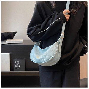 Detail of light blue crescent bag showing grainy leather texture and gold hardware