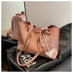 Detail of pink lychee leather tote bag with decorative heart pattern silk scarf and strap