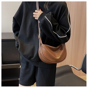 Detailed close-up of brown lychee pattern leather half-moon bag with gold lettering