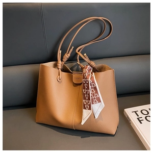 Detail of a brown leather tote bag with lychee texture and decorative silk scarf
