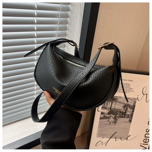 Detail of black lychee grain leather crescent bag with gold buckle and fashion text