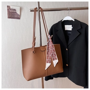 Detail of brown litchi pattern leather tote bag with decorative silk scarf on shoulder strap